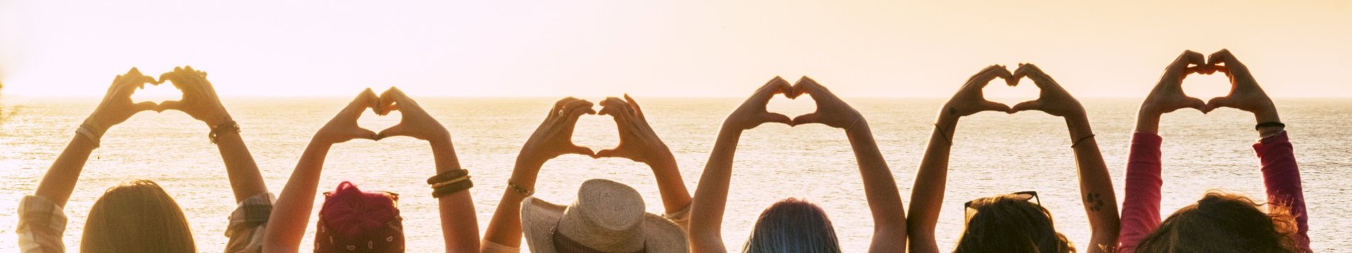 Ladies sat in a row making love hearts with their hands