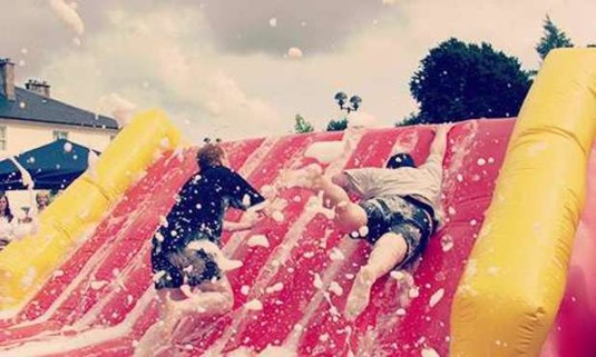Two men trying to climb a foam filled slide. Discover Barcelona Inflatable Games from Hen Weekends: