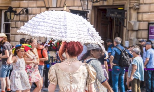 A lady in period clothing and parasol taking a Bridgerton walking tour of bath on her hen do