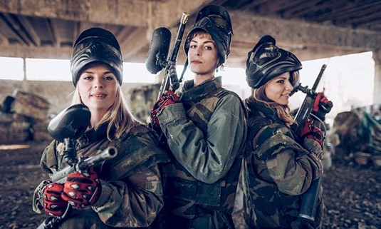 Three girls taking part in paintballing.