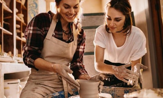 2 women In a pottery class making ceramic cups on a hen do activity