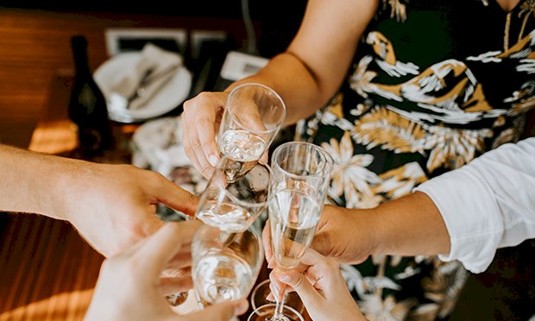 Four ladies hold glasses of prosecco together 