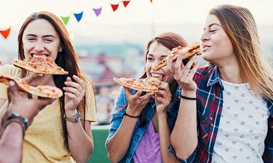 Three ladies enjoying pizza on their hen weekend.
