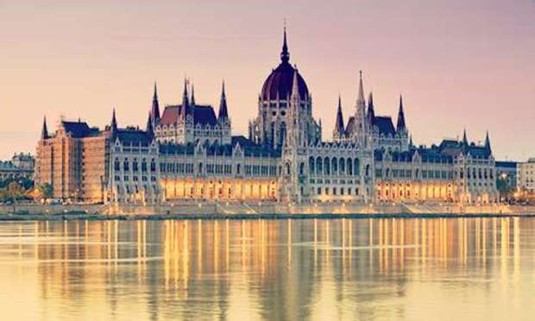 Pink skies over the Budapest Parliament Building with lights shining off the river. Explore Budapest Hen Party ideas below: