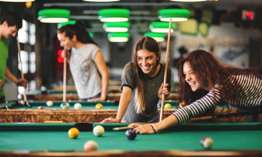Women playing a game of american pool on a hen do