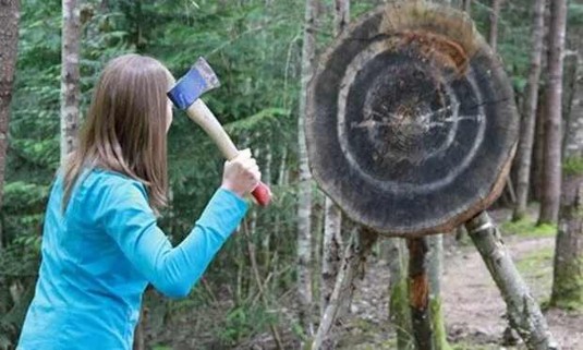 Woman axe throwing at target in forest