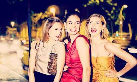 Girls smiling and laughing on a night out wearing beige, yellow and red. Discover Italy Hen Party ideas below: