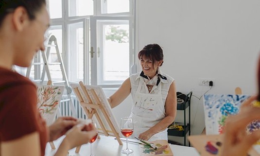 Two Ladies painting a canvas with a glass of wine each