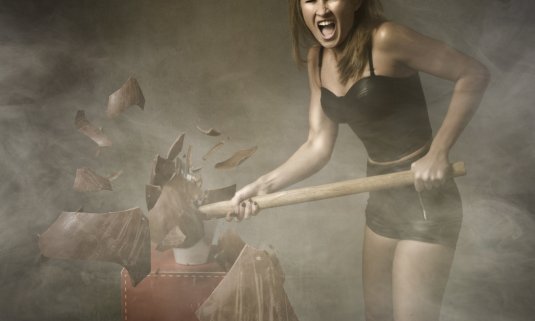 woman smashing up a rage room with a mallet