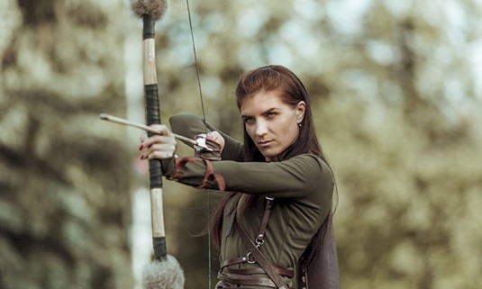 A lady pulling back a crossbow.