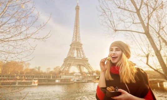 A lady enjoying some street food Infront of the Eiffel tower