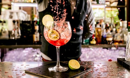 Bartender pouring cocktails into glass 